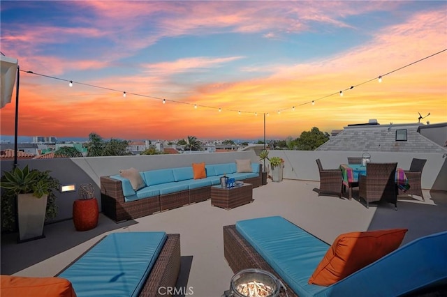 patio terrace at dusk with an outdoor living space with a fire pit