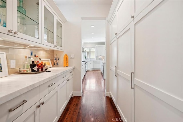 bar featuring light stone countertops, white cabinets, tasteful backsplash, and dark wood-type flooring