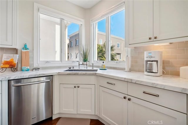 kitchen with white cabinetry, dishwasher, light stone countertops, sink, and decorative backsplash