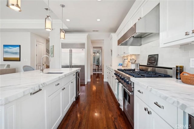 kitchen with premium appliances, dark wood-type flooring, sink, pendant lighting, and white cabinetry