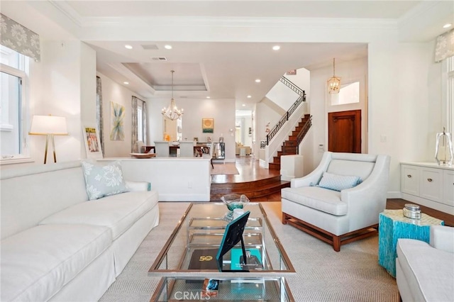 living room featuring light hardwood / wood-style floors, an inviting chandelier, and a tray ceiling