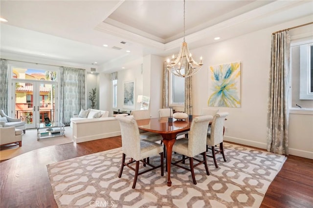 dining room featuring a raised ceiling, an inviting chandelier, and hardwood / wood-style flooring