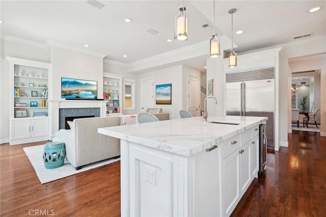 kitchen with white cabinetry, sink, dark wood-type flooring, an island with sink, and decorative light fixtures