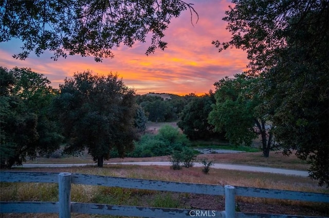 yard at dusk featuring a rural view