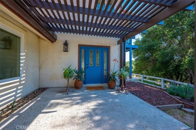 view of exterior entry featuring a patio area and a pergola