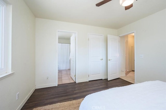 bedroom with ceiling fan, dark wood-type flooring, and ensuite bath