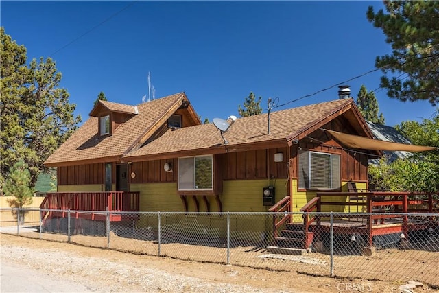 view of front of property featuring roof with shingles, board and batten siding, and fence