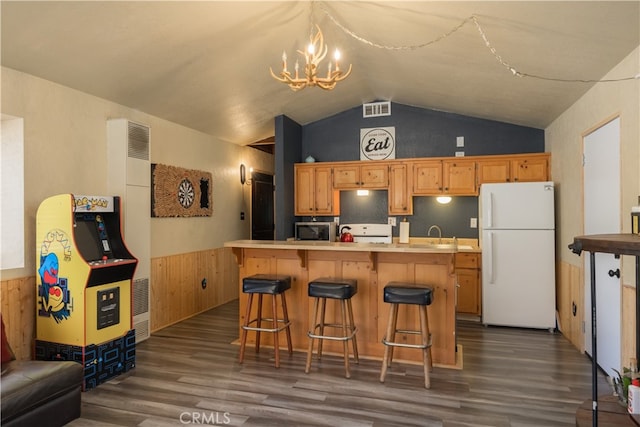 kitchen with dark hardwood / wood-style floors, white appliances, an inviting chandelier, and a kitchen bar