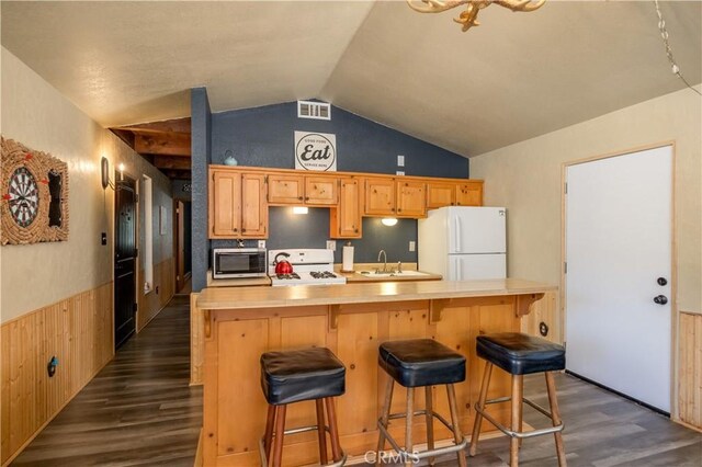 kitchen featuring a breakfast bar area, lofted ceiling, dark wood-type flooring, and white appliances