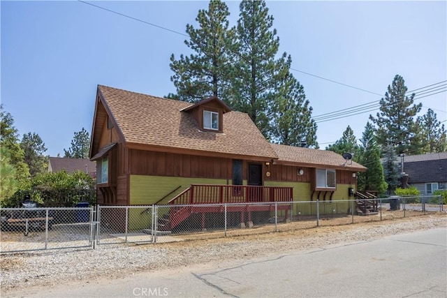 chalet / cabin featuring a fenced front yard, a shingled roof, and a gate