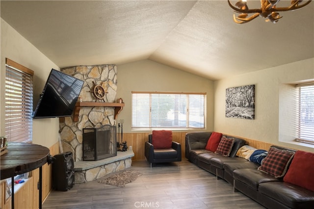 living room with vaulted ceiling, a fireplace, wood walls, a textured ceiling, and hardwood / wood-style floors