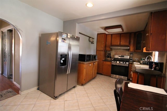 kitchen with sink, stainless steel appliances, backsplash, and light tile patterned floors