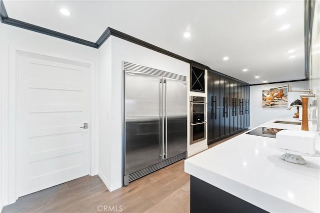 kitchen featuring wood-type flooring, stainless steel appliances, and ornamental molding