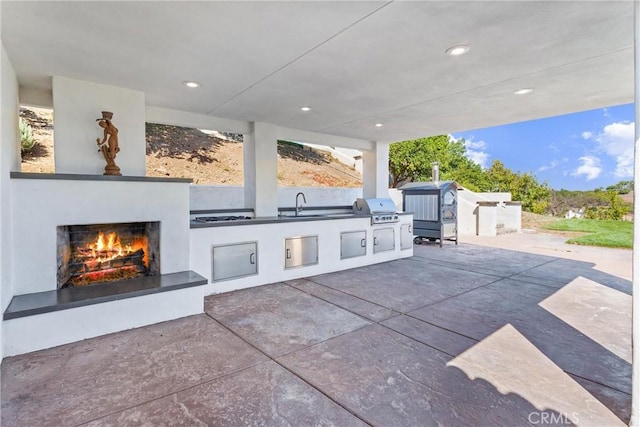 view of patio with sink, area for grilling, an outdoor fireplace, and exterior kitchen