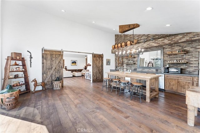 bar featuring stainless steel dishwasher, decorative light fixtures, a barn door, and dark hardwood / wood-style floors