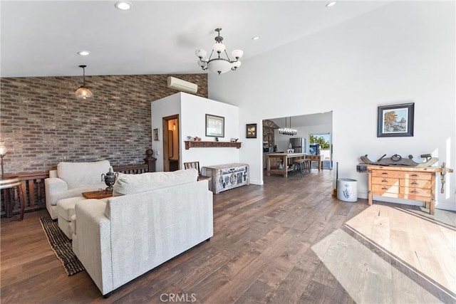 living room with high vaulted ceiling, an inviting chandelier, dark hardwood / wood-style floors, brick wall, and a wall unit AC