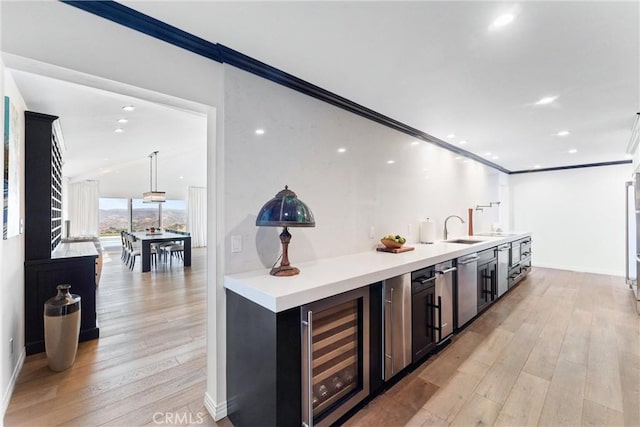 kitchen featuring crown molding, sink, beverage cooler, and light hardwood / wood-style floors