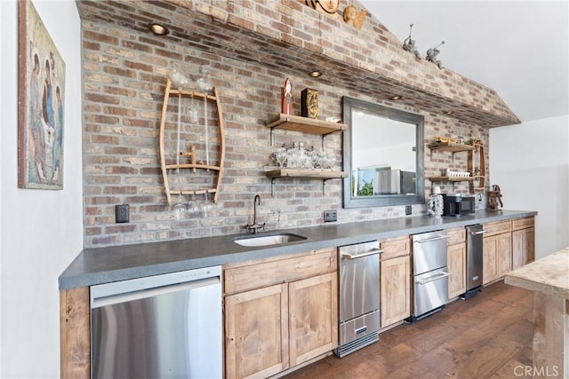 bar featuring dark wood-type flooring, stainless steel dishwasher, brick wall, and sink