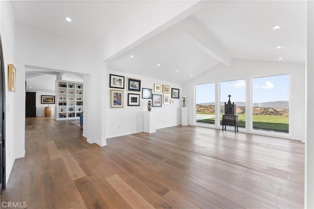 unfurnished living room with vaulted ceiling with beams and light hardwood / wood-style floors