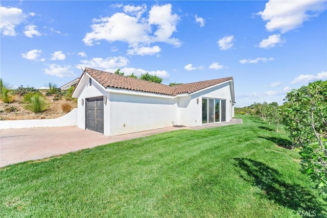 back of house with a garage and a lawn