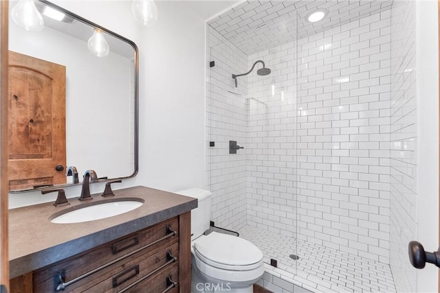 bathroom featuring a tile shower, vanity, and toilet