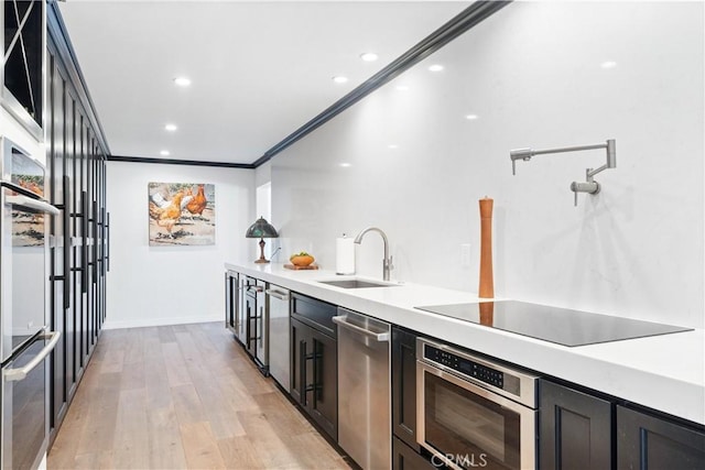 kitchen with dishwasher, sink, black electric cooktop, light wood-type flooring, and ornamental molding