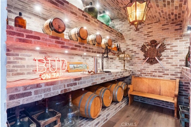 bar with hardwood / wood-style flooring, brick ceiling, and brick wall