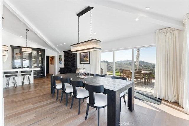 dining area with a mountain view, hardwood / wood-style floors, and lofted ceiling with beams