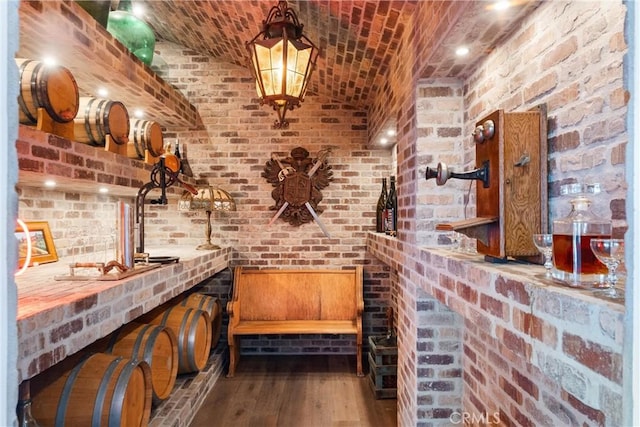 wine area featuring brick ceiling, hardwood / wood-style floors, and brick wall