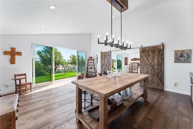 dining space featuring high vaulted ceiling, a barn door, wood-type flooring, and a wealth of natural light