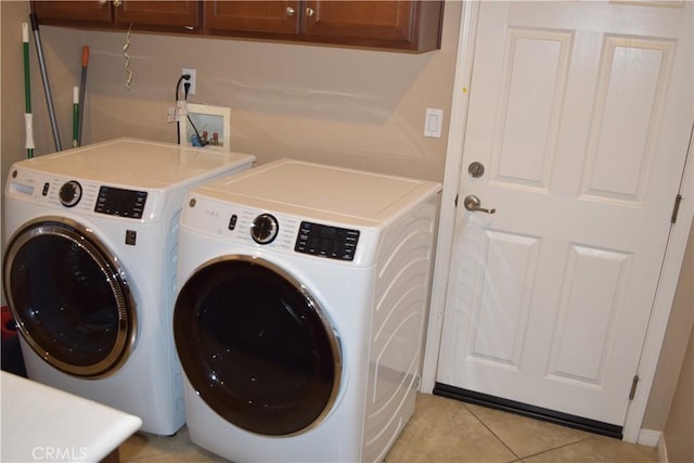 laundry room with light tile patterned floors, washing machine and dryer, and cabinet space