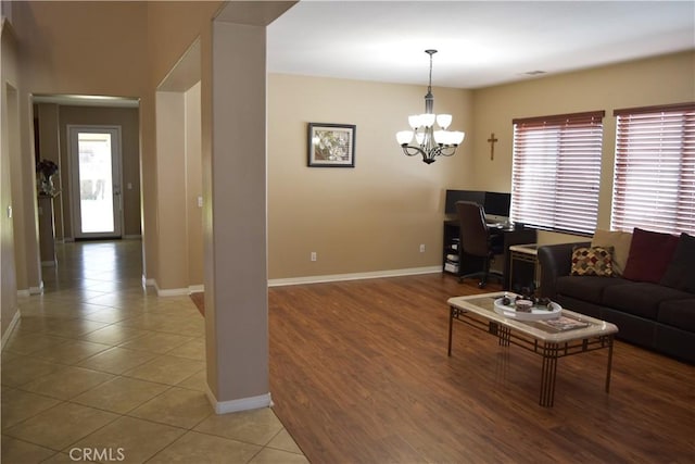 living area featuring plenty of natural light, a chandelier, and baseboards