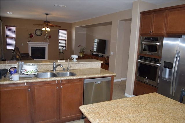 kitchen featuring stainless steel appliances, a fireplace, a sink, visible vents, and open floor plan