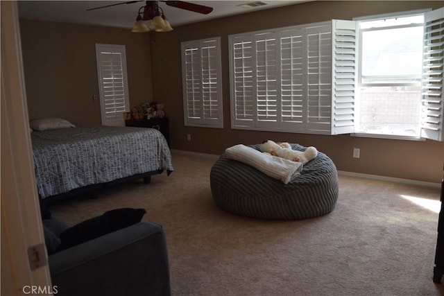 carpeted bedroom featuring ceiling fan, visible vents, and baseboards