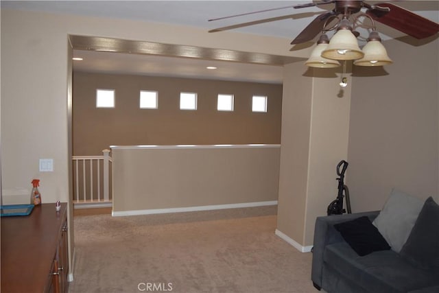 unfurnished room featuring a wealth of natural light, baseboards, carpet flooring, and an upstairs landing