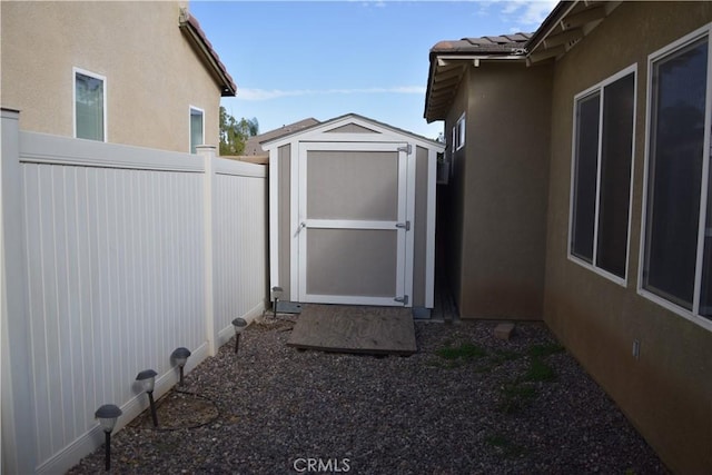 exterior space with a tile roof, stucco siding, a shed, a fenced backyard, and an outdoor structure