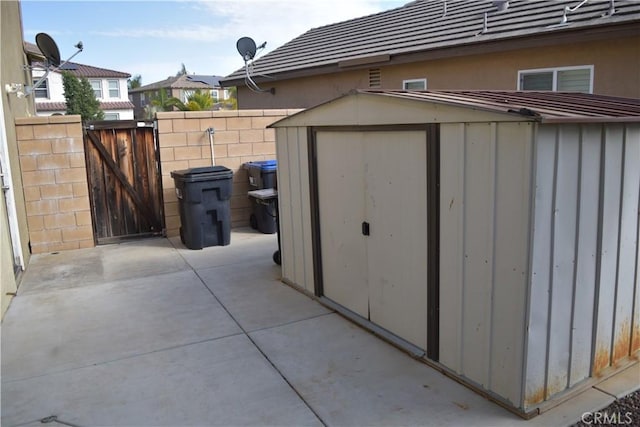 view of shed featuring fence and a gate