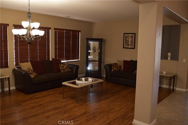 living area with a chandelier, baseboards, and wood finished floors