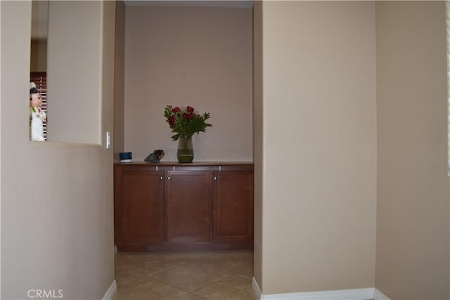 corridor with light tile patterned floors and baseboards