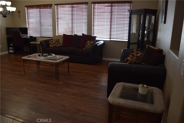 living area with a notable chandelier, baseboards, and wood finished floors