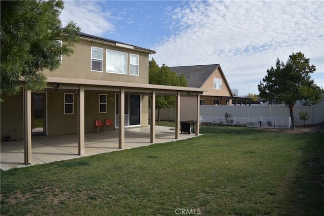 back of house with stucco siding, fence, a patio, and a yard