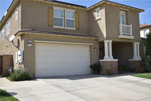 view of front of house featuring a garage, concrete driveway, a balcony, and stucco siding