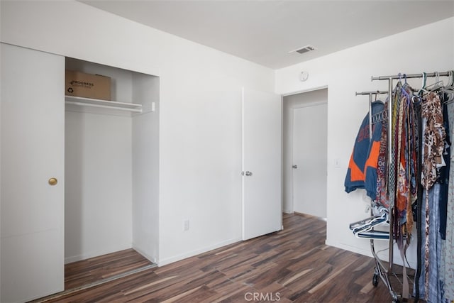 unfurnished bedroom featuring a closet and dark wood-type flooring