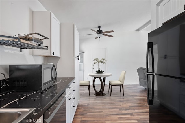 kitchen with vaulted ceiling with beams, stainless steel dishwasher, white cabinetry, dark stone counters, and hardwood / wood-style floors