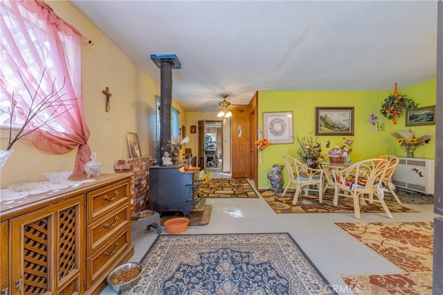 interior space featuring ceiling fan, radiator heating unit, carpet, and a wood stove