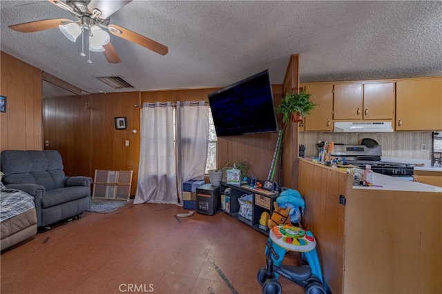 living room featuring a textured ceiling, wood walls, and ceiling fan