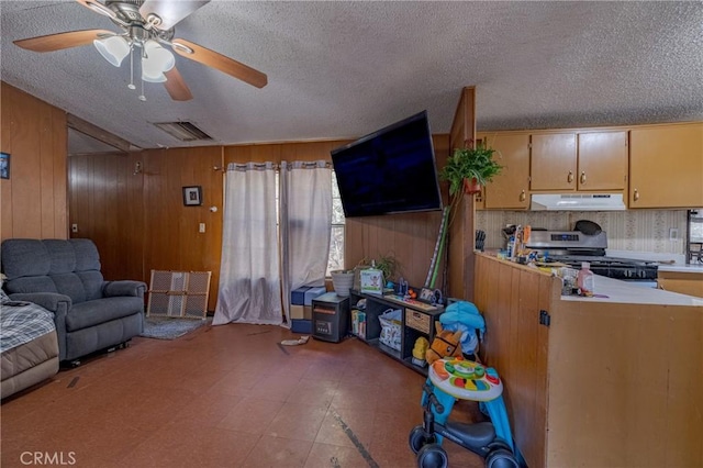 living room with visible vents, wood walls, ceiling fan, and a textured ceiling