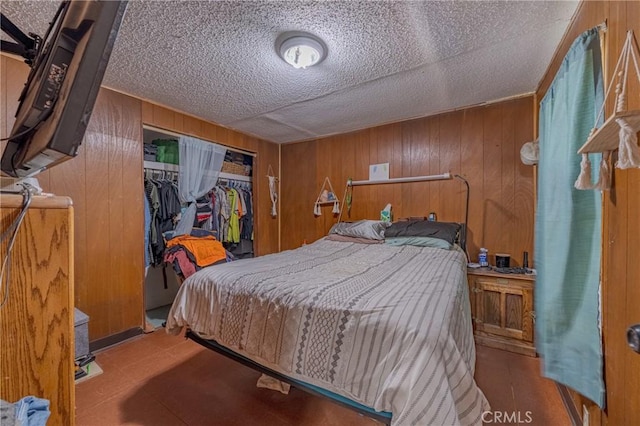 bedroom featuring wood walls, a textured ceiling, and a closet