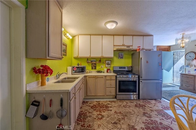 kitchen featuring under cabinet range hood, appliances with stainless steel finishes, light countertops, a sink, and a textured ceiling
