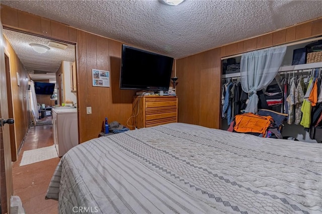 bedroom with wood walls, a textured ceiling, and a closet